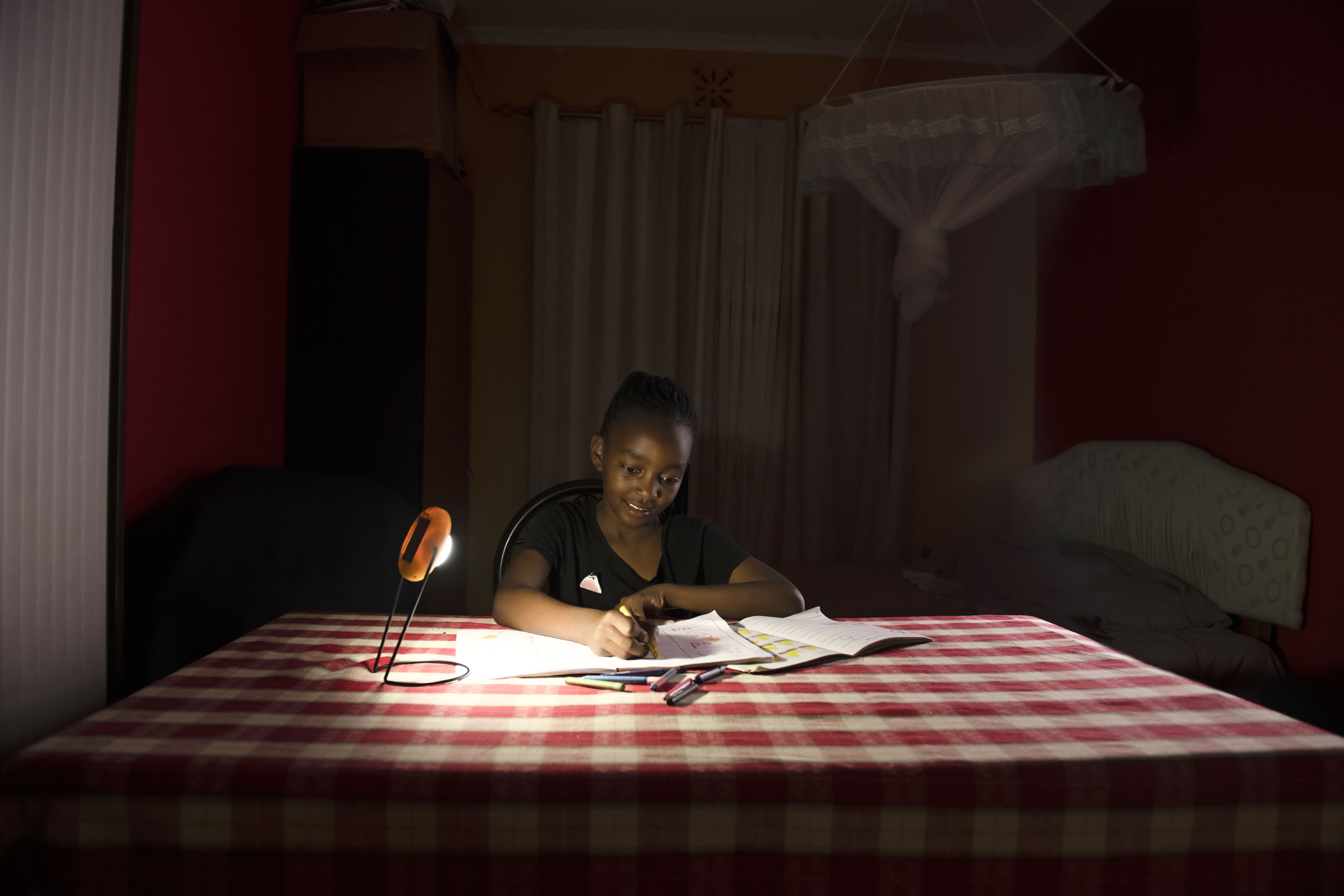 Young boy uses a Sun King Pico Plus solar powered lantern to help him study at night.