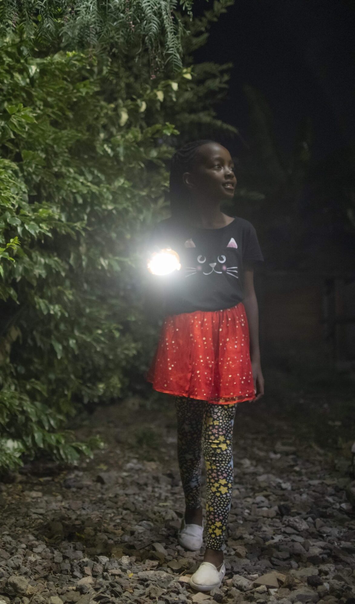 Young girl lights up her path at nighttime using a Sun King Pico Plus portable solar powered lantern.